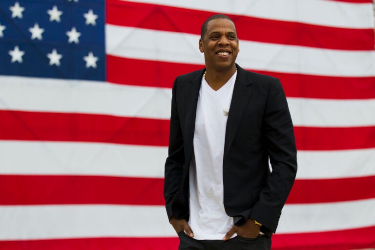 Jay-Z standing in front of a large American flag