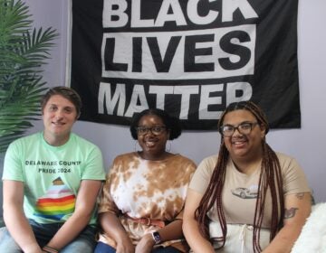 Kyle McIntyre, Dyamond Gibbs and Kayla Cocci are seen sitting on a couch under a Black Lives Matter banner