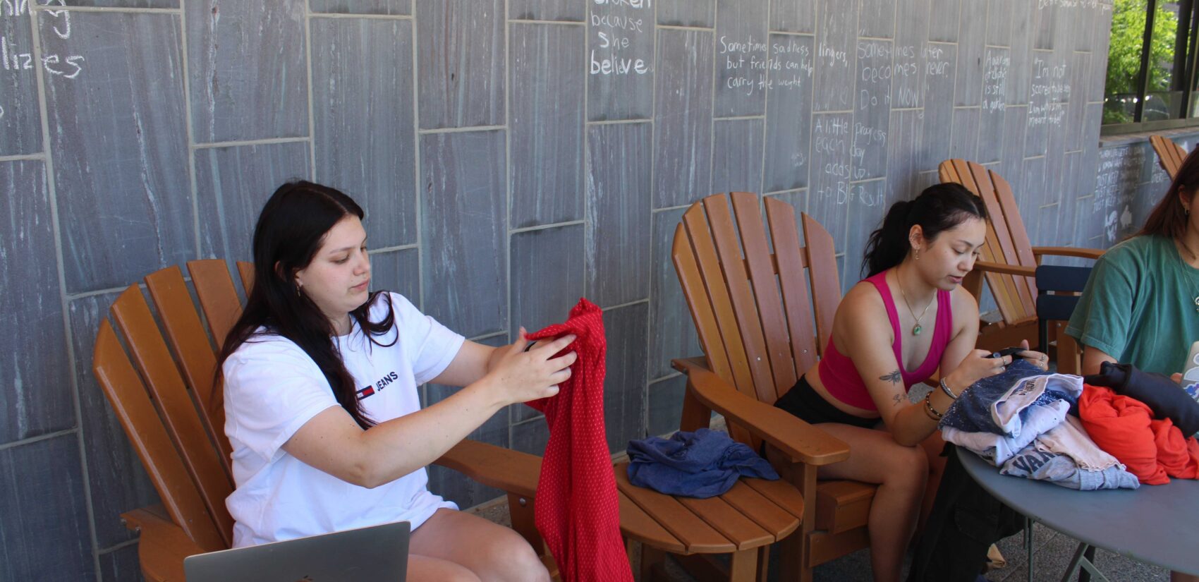 Addie Schenkel, left, a recent Drexel graduate, examines an item of donated clothing. She and other students are working with Professor Rachel Higgins to collect data on clothing discarded by students during move out. (Emily Neil/WHYY)