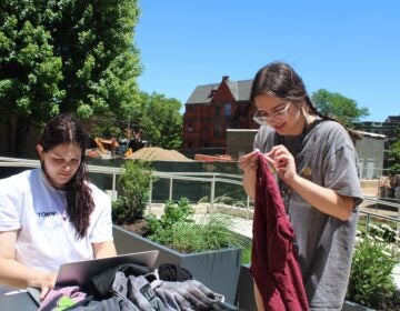Addie Schenkel, left, a recent Drexel graduate, and Arianna Papadakis, right, a rising junior, work together to collect data on clothing discarded by students during move out. (Emily Neil/WHYY)