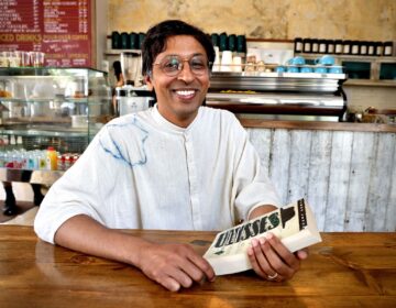 Nikil Saval posing for a photo in a coffeeshop with the book 'Ulysses'