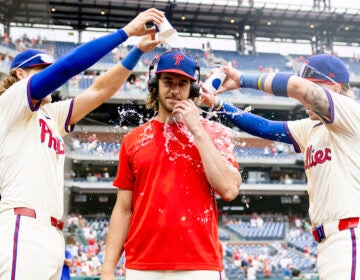 Philadelphia Phillies starting pitcher Aaron Nola is doused with water by Alec Bohm, left, and Bryson Stot