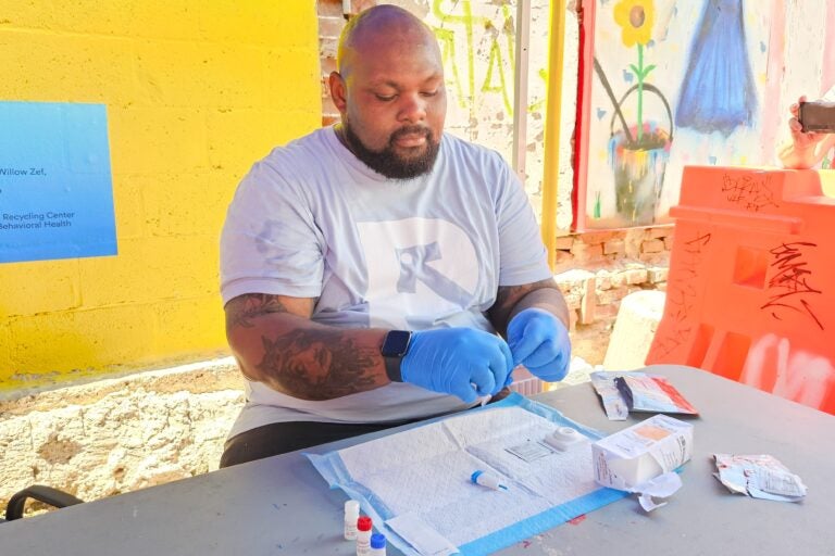 Kareem Mims, prevention health care coordinator at Prevention Point Philadelphia in Kensington, prepares a rapid HIV test, which involves a small finger prick and results in about 60 seconds. (Nicole Leonard/WHYY)
