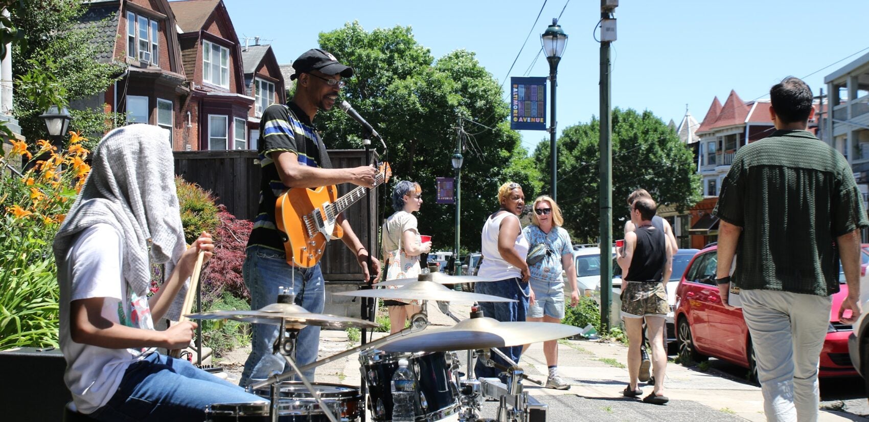 Porchfest attendees watch two people play guitar and drums