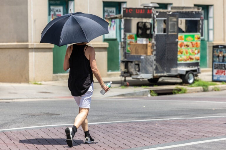07 09 2024 k paynter heat wave general-6 A person walkng down the street with an umbrella to get out of the sun