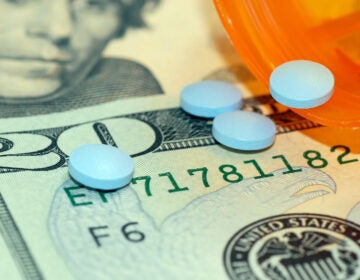 Medication pills on top of US currency. (Bigstock/jpimages)