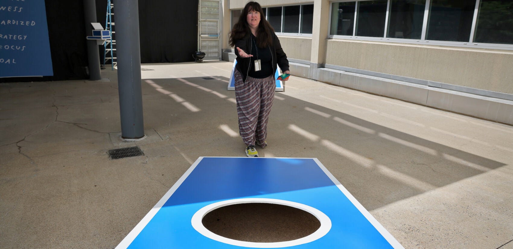 Kate Abercrombie, artist and registrar at the Institute of Contemporary Art, plays with the oversized cornhole game that is part of the exhibit ''Where I Learned to Look: Art From the Yard.'' (Emma Lee/WHYY)