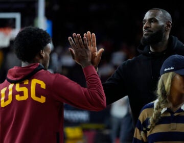 Southern California guard Bronny James, left, high-fives his father, Los Angeles Lakers' LeBron James, as he warms up before an NCAA college basketball game against Stanford in Los Angeles, Saturday, Jan. 6, 2024. (AP Photo/Ashley Landis)
