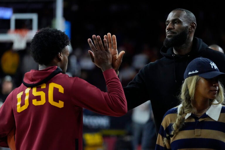 Southern California guard Bronny James, left, high-fives his father, Los Angeles Lakers' LeBron James, as he warms up before an NCAA college basketball game against Stanford in Los Angeles, Saturday, Jan. 6, 2024. (AP Photo/Ashley Landis)