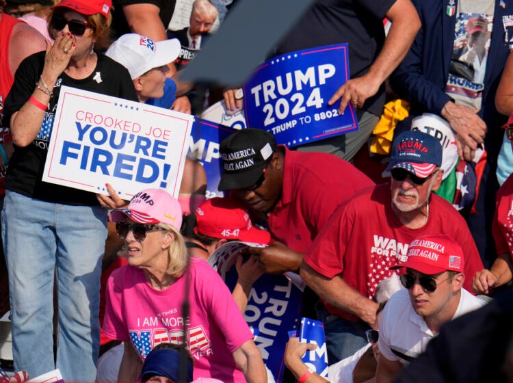 Members of the crowd react as U.S. Secret Service agents surround Republican presidential candidate former President Donald Trump at a campaign event in Butler, Pa., on Saturday, July 13, 2024. (AP Photo/Gene J. Puskar)