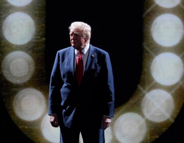 Donald Trump stands in front of a ring of circular lights