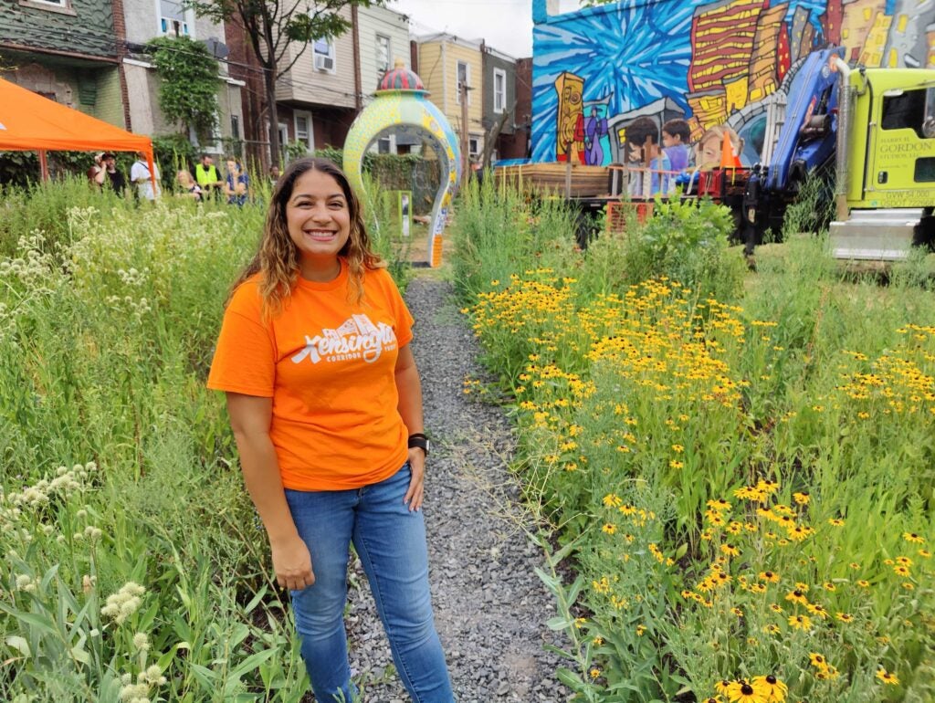 Jasmon Velez of the Kensington Corridor Trust stands in the native flower garden where the the first of three "We Here" sculptures was erected by Mural Arts Philadelphia. 