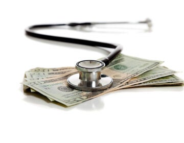 A stethoscope and American money on a white background - Healtcare cost concept
