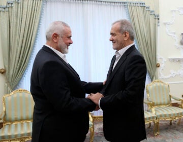 In this photo released by the Iranian Presidency Office, President Masoud Pezeshkian, right, shakes hands with Hamas chief Ismail Haniyeh at the start of their meeting at the President's office in Tehran, Iran, Tuesday, July 30, 2024.