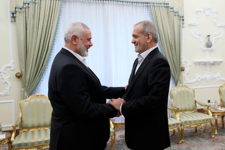 In this photo released by the Iranian Presidency Office, President Masoud Pezeshkian, right, shakes hands with Hamas chief Ismail Haniyeh at the start of their meeting at the President's office in Tehran, Iran, Tuesday, July 30, 2024.