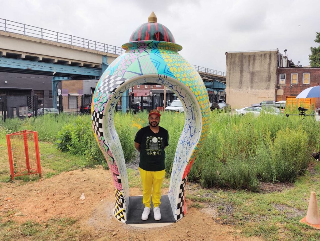 Roberto Lugp stands by a sculpture