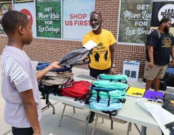 David Chaney, Sr. hands a backpack to a child at a giveaway