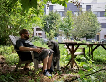 Jordan Baumgarten sits in a chair with his dog