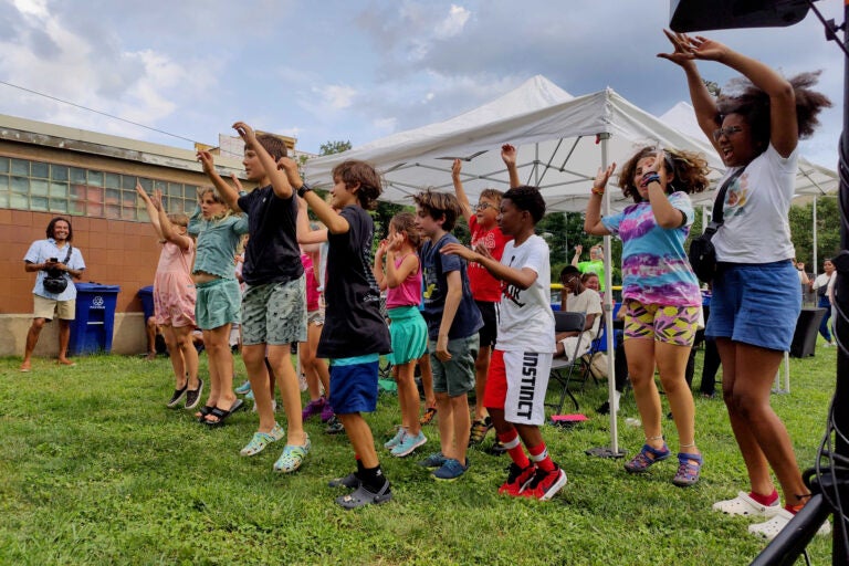 The children who helped design Calo Rosa's new mural on the Markward Recreation Center celebrate with an ''arts jump'' during the mural's dedication ceremony. it is the first of six planned rec center murals, funded by Mural Arts and the Pennsylvania Commission on Crime and Delinquency, aimed at reducing violence by engaging at-risk communities in the creation of art. (Peter Crimmins/WHYY)