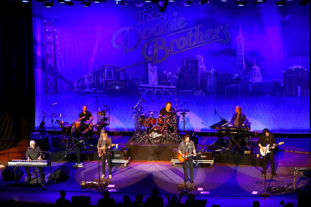 Several men play instruments on stage as part of a Dobbie Brothers concert