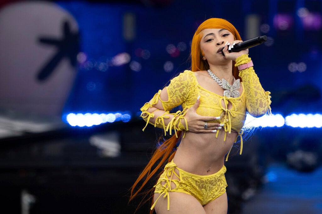 A female rapper performs on stage holding a microphone to her mouth