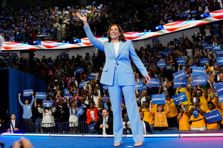 Kamala Harris waves on a stage in front of a crowd of people