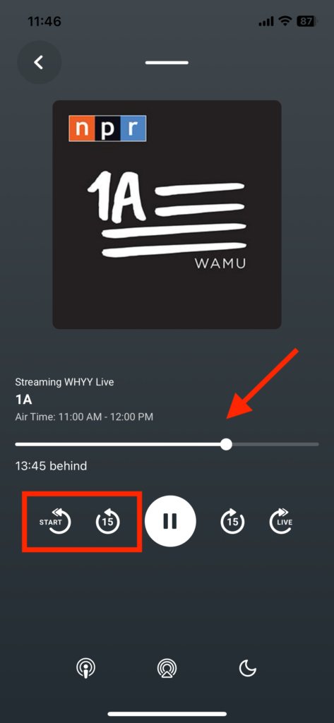 A mobile app screen displaying the WHYY Listen app's live radio stream of the show "1A" airing from 11:00 AM to 12:00 PM. The screen shows playback controls, including a button to rewind to the start of the show, a 15-second rewind button, a pause button, a 15-second forward button, and a button to switch to the live broadcast. The playback progress bar indicates the user is 13 minutes and 45 seconds behind the live stream. The app's interface features a dark background with white icons and text.  An image of the '1A' logo is displayed at the top of the screen.