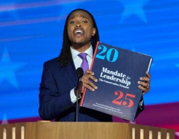 Malcolm Kenyatta holds an enlarged Project 2025 book