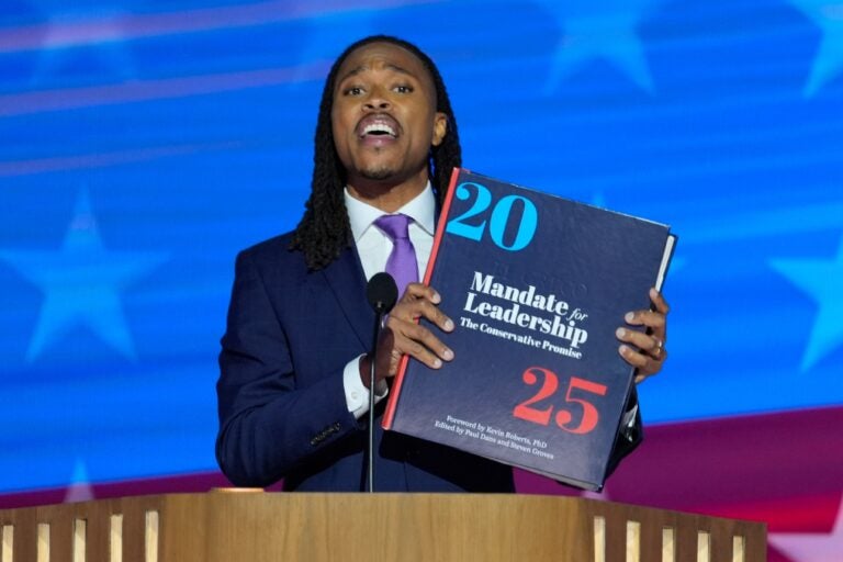 Malcolm Kenyatta holds an enlarged Project 2025 book