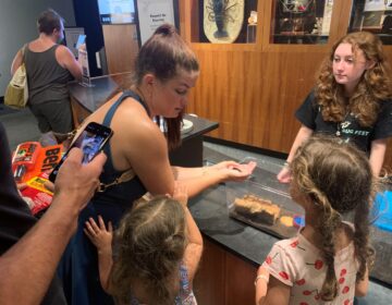 A woman shows two children a cockroach at Bug Fest in Phialdelphia