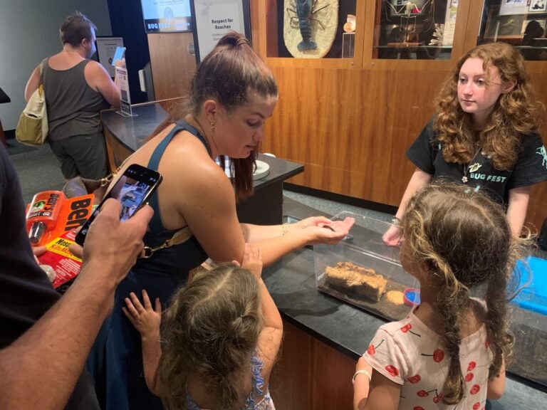 A woman shows two children a cockroach at Bug Fest in Phialdelphia