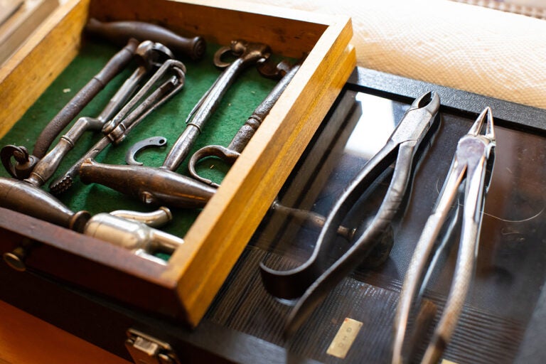 A selection of old dental tools sit in an open drawer