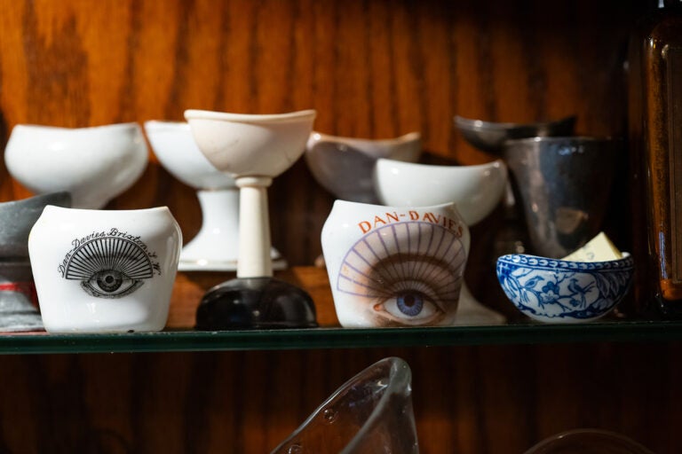 A collection of cups, some with eyes painted on them, sit on a shelf