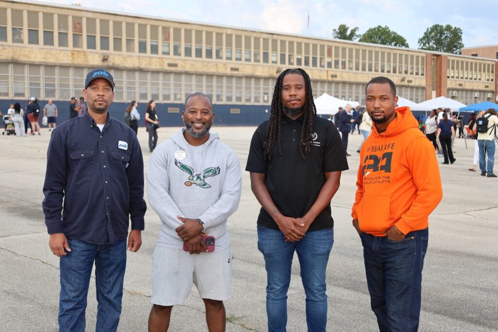 4 men posing for a photo outside of school