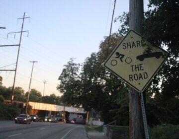 a sign on Chester Pike reads Share the Road and has symbols for a cyclist and car