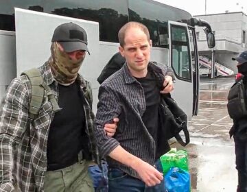 Evan Gershkovich is escorted by a Russian Federal Security Service agent