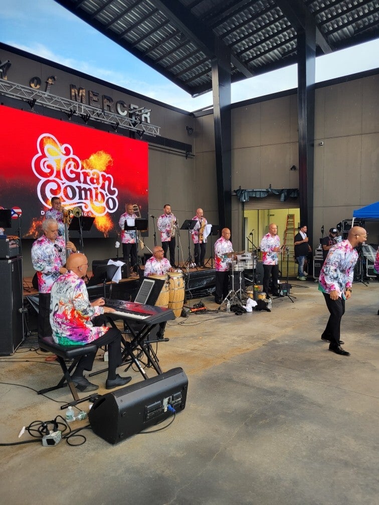 A Latino musical act performs with a screen reading "El Gran Combo" behind them