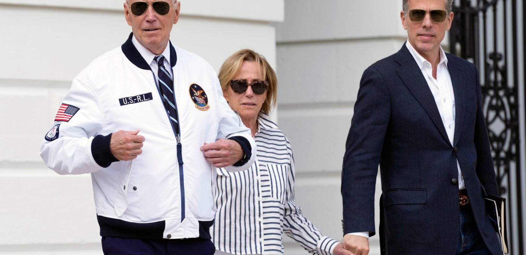 President Joe Biden, from left, walking with his sister Valerie Biden Owens and his son Hunter Biden, shows off his Team USA jacket as he walks toward Marine One on the South Lawn of the White House in Washington, Friday, July 26, 2024, en route to Camp David for the weekend. (AP Photo/Susan Walsh)