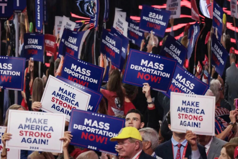 Attendees at the Republican National Convention hold up signs reading Mass Deportation Now!