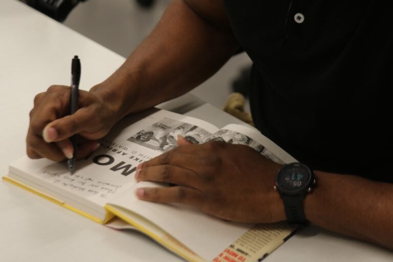 Mike Africa Jr.'s hands on a book he's signing