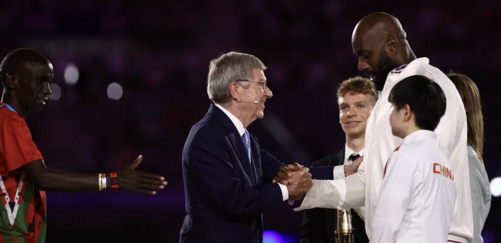 International Olympic Committee President Thomas Bach (center) shakes hands with France's judoka Teddy Riner on Sunday