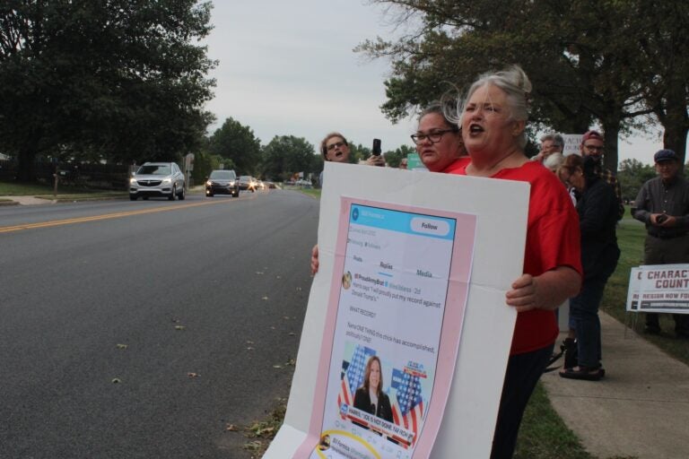 A community member holds a sign calling for Bill Formica's resignation outside a school board meeting