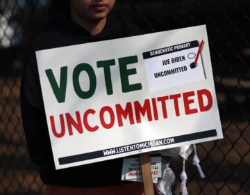 a sign reads Vote Uncommitted with check boxes for Joe Biden and Uncommitted, with the latter checked