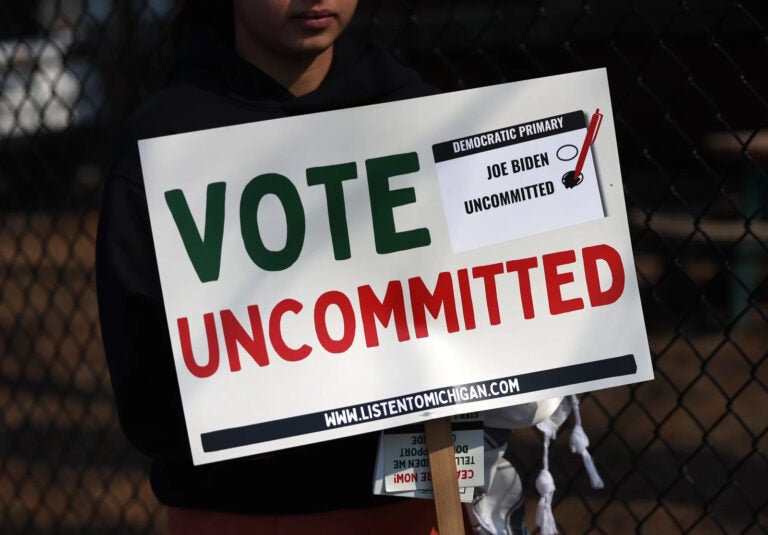 a sign reads Vote Uncommitted with check boxes for Joe Biden and Uncommitted, with the latter checked