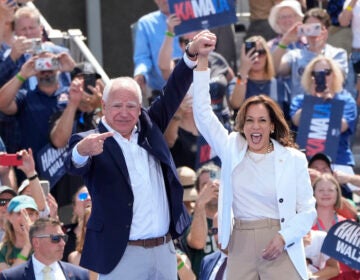 Kamala Harris and Tim Walz raising their hands together on stage