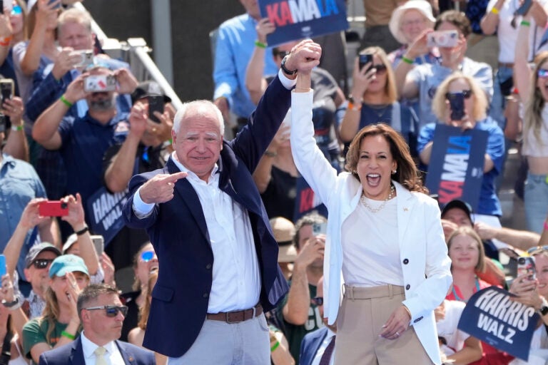 Kamala Harris and Tim Walz raising their hands together on stage