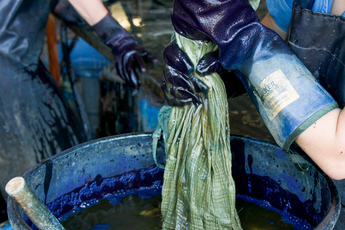 a dress held in hands being dyed