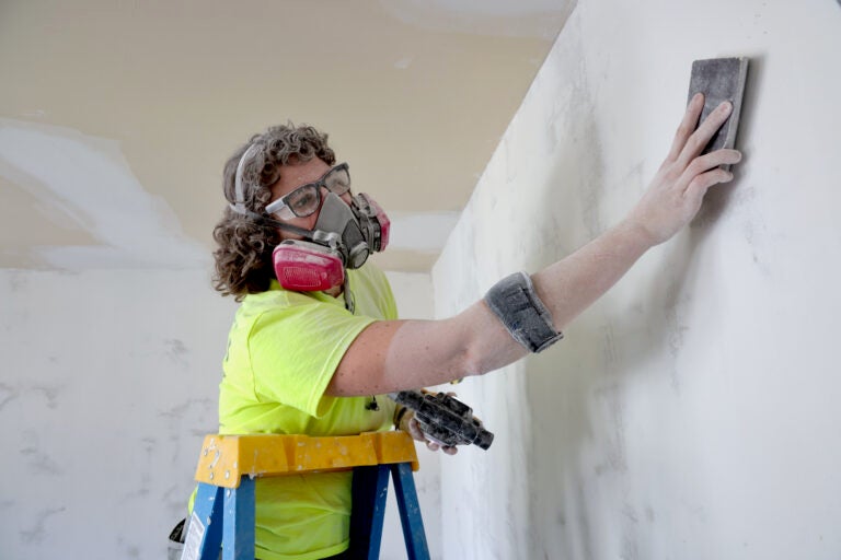 A person wearing a gas mask works on a home