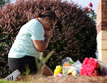 Linda Carter, of Grayson, Ga., kneels near Apalachee High School to place flowers as she mourns for the slain students and teachers on Thursday, Sept. 5, 2024, in Winder, Ga.