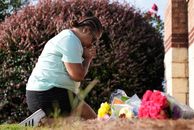 Linda Carter, of Grayson, Ga., kneels near Apalachee High School to place flowers as she mourns for the slain students and teachers on Thursday, Sept. 5, 2024, in Winder, Ga.